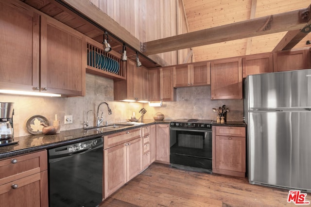 kitchen featuring dark stone countertops, sink, black appliances, and light wood-type flooring