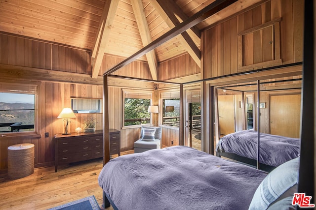 bedroom with beamed ceiling, light wood-type flooring, wooden walls, and wooden ceiling