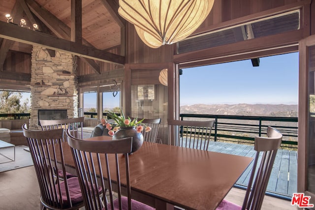 dining space with a mountain view, hardwood / wood-style floors, high vaulted ceiling, and a stone fireplace