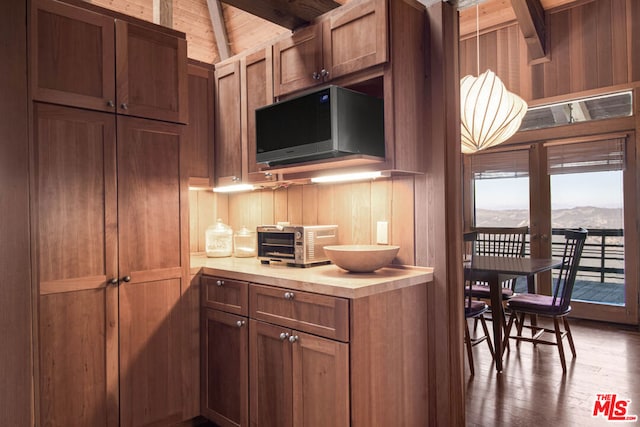 kitchen featuring a mountain view, wood walls, vaulted ceiling with beams, dark hardwood / wood-style floors, and wood ceiling