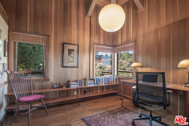 office space with wood walls, a towering ceiling, and wood-type flooring