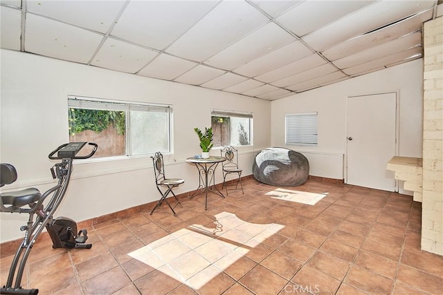 living area with vaulted ceiling, a drop ceiling, and light tile patterned flooring