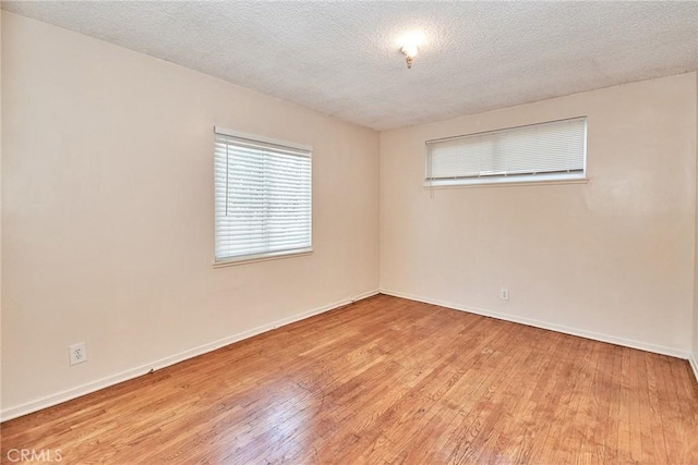 empty room with light wood-type flooring and a textured ceiling