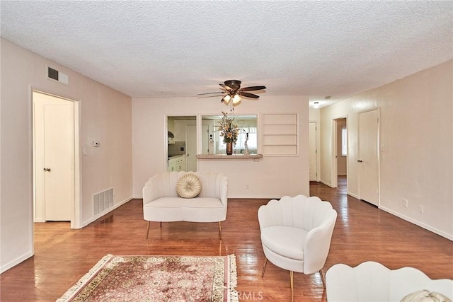 living room featuring hardwood / wood-style floors, ceiling fan, and a textured ceiling