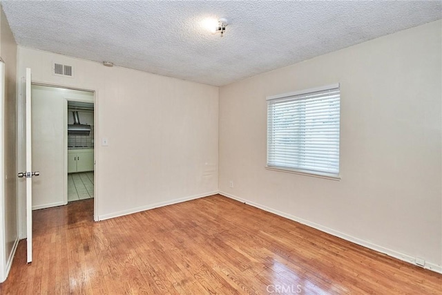 empty room with light hardwood / wood-style floors and a textured ceiling