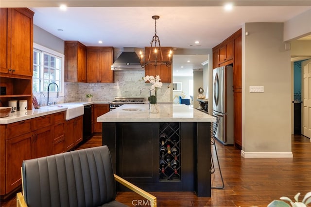 kitchen featuring a center island, wall chimney range hood, dark hardwood / wood-style floors, appliances with stainless steel finishes, and decorative light fixtures