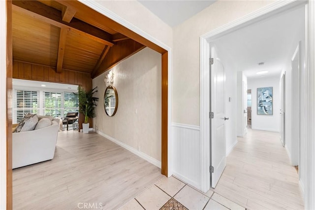 hall featuring vaulted ceiling with beams, light hardwood / wood-style flooring, and wood ceiling