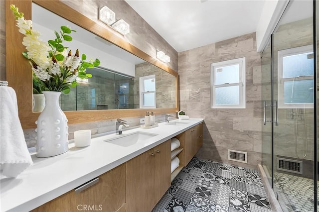 bathroom featuring vanity, a wealth of natural light, a shower with shower door, and tile walls