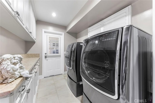 washroom featuring separate washer and dryer, light tile patterned floors, and cabinets