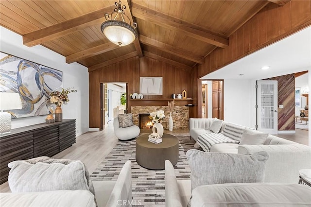 living room with vaulted ceiling with beams, a fireplace, wooden ceiling, and light wood-type flooring