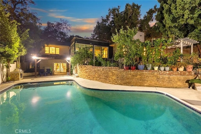 pool at dusk with a patio area