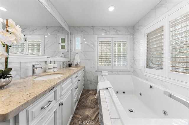 bathroom with vanity, tile walls, and tiled tub