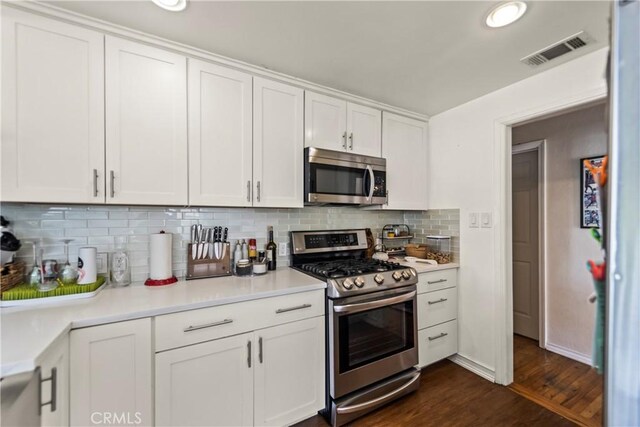 kitchen featuring backsplash, appliances with stainless steel finishes, dark hardwood / wood-style floors, and white cabinets