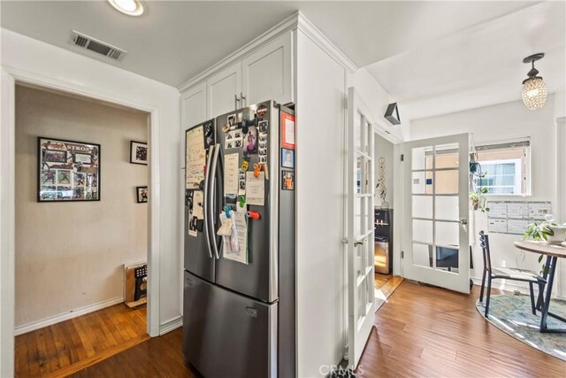 kitchen featuring hardwood / wood-style floors, white cabinets, and stainless steel refrigerator