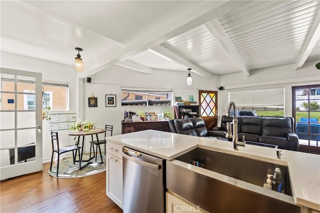 kitchen with white cabinets, light countertops, stainless steel dishwasher, light wood-type flooring, and pendant lighting