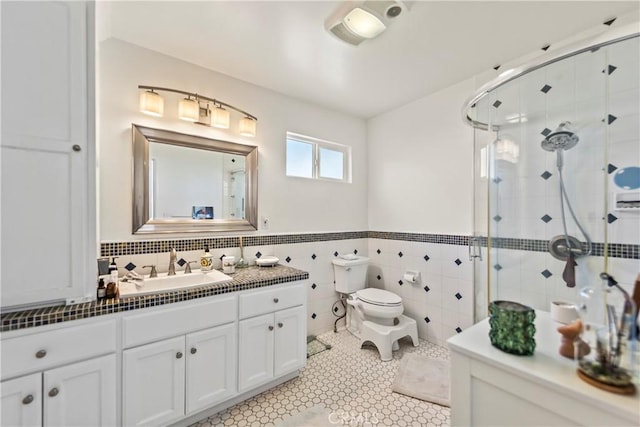 bathroom with toilet, a wainscoted wall, vanity, tile walls, and a shower stall