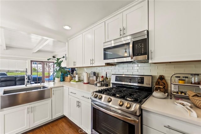 kitchen with a sink, stainless steel appliances, light countertops, and white cabinetry