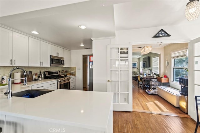 kitchen with stainless steel appliances, white cabinets, light countertops, and a peninsula