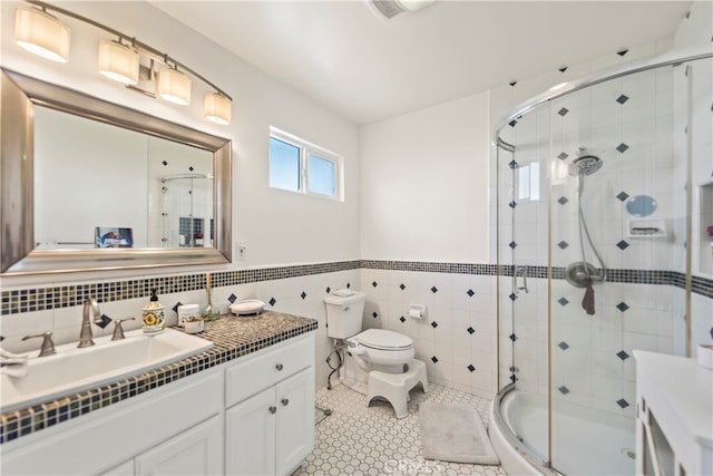 bathroom with tile walls, vanity, toilet, and walk in shower