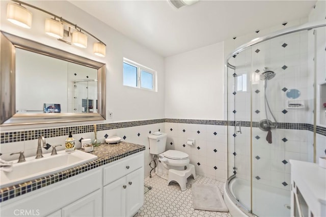 bathroom featuring tile walls, a shower stall, vanity, and toilet