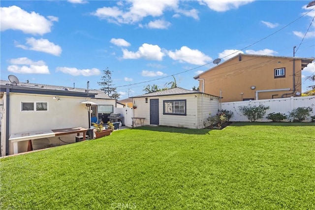 rear view of property with an outbuilding, a lawn, and fence