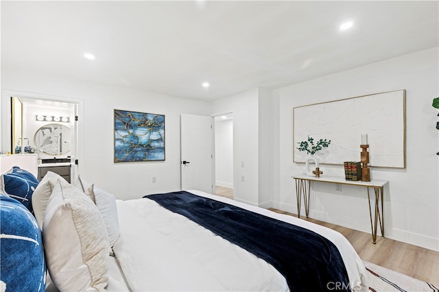 bedroom with connected bathroom and light wood-type flooring