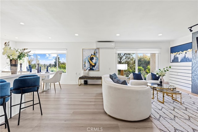 living room featuring an AC wall unit and light hardwood / wood-style flooring