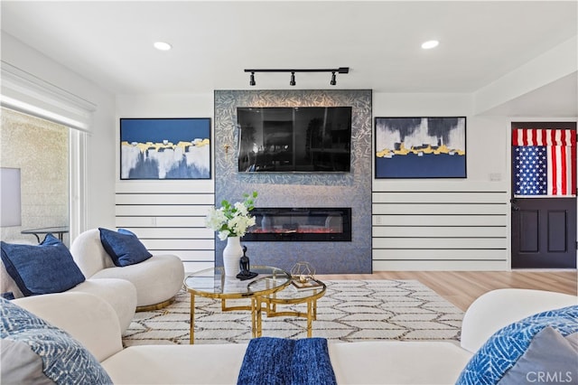 living room featuring track lighting, wood-type flooring, and a large fireplace