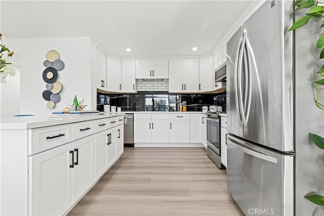 kitchen featuring kitchen peninsula, white cabinets, backsplash, light wood-type flooring, and stainless steel appliances