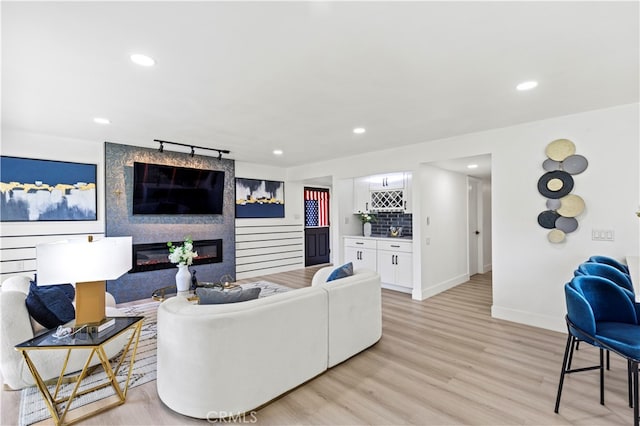 living room with bar area, light hardwood / wood-style flooring, and a large fireplace