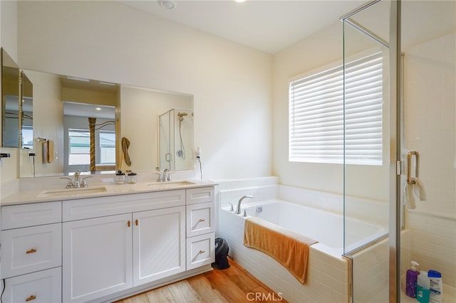 bathroom with vanity, independent shower and bath, hardwood / wood-style flooring, and a healthy amount of sunlight