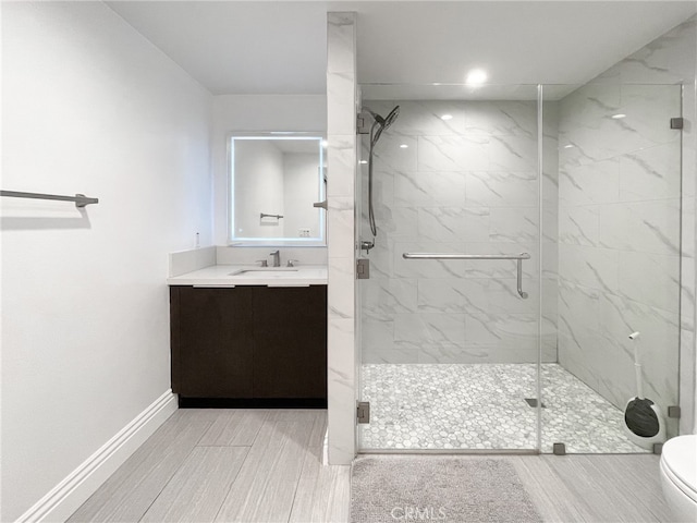 bathroom with toilet, vanity, and a shower with door