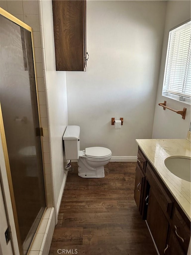 bathroom with vanity, toilet, a shower with shower door, and wood-type flooring