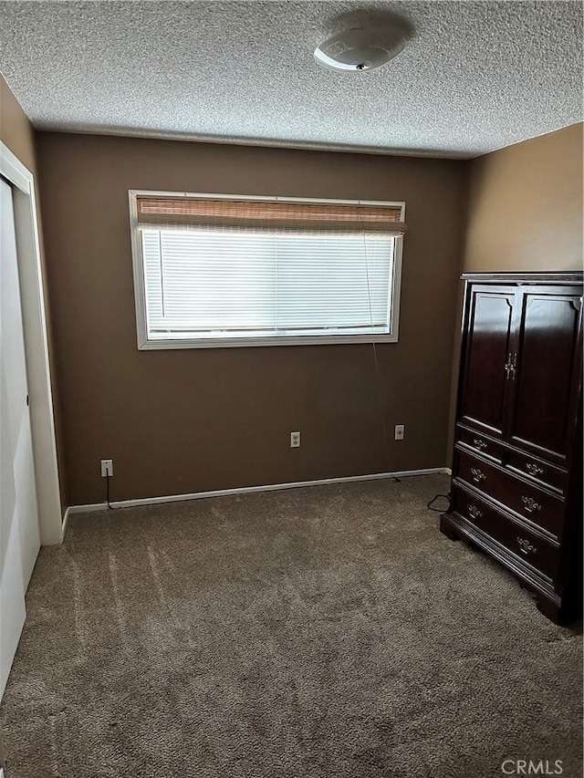 unfurnished bedroom with dark colored carpet and a textured ceiling