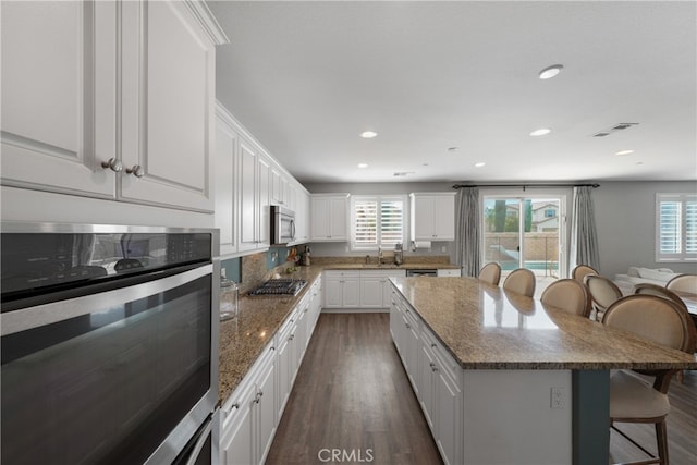 kitchen with appliances with stainless steel finishes, white cabinets, and plenty of natural light