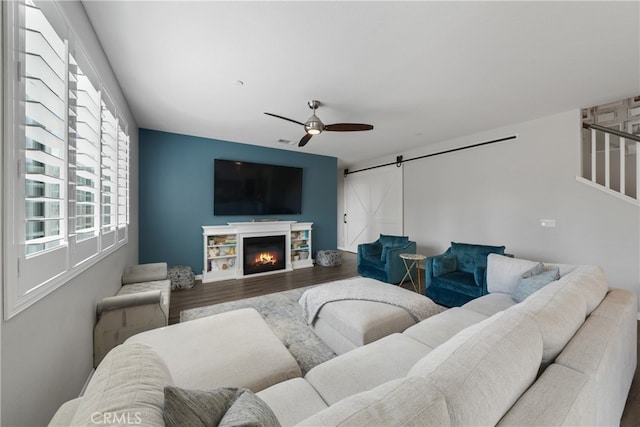 living room with hardwood / wood-style floors, a barn door, and ceiling fan