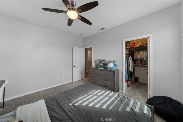 bedroom with a closet, a spacious closet, light colored carpet, and ceiling fan