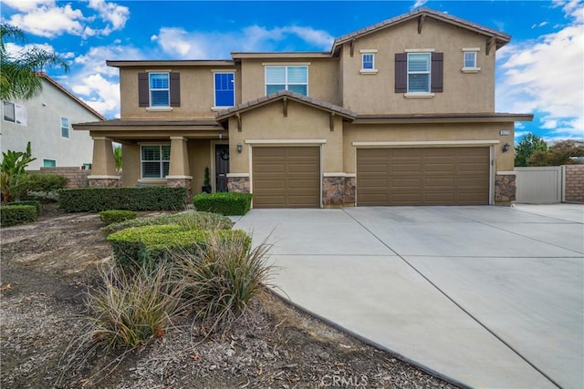 view of front of home featuring stucco siding, an attached garage, fence, stone siding, and driveway