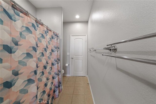 bathroom with toilet, curtained shower, and tile patterned flooring