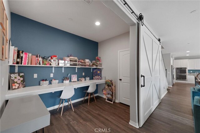 office featuring a barn door and dark hardwood / wood-style floors