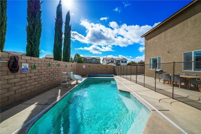 view of pool with a fenced backyard, a water slide, and a patio