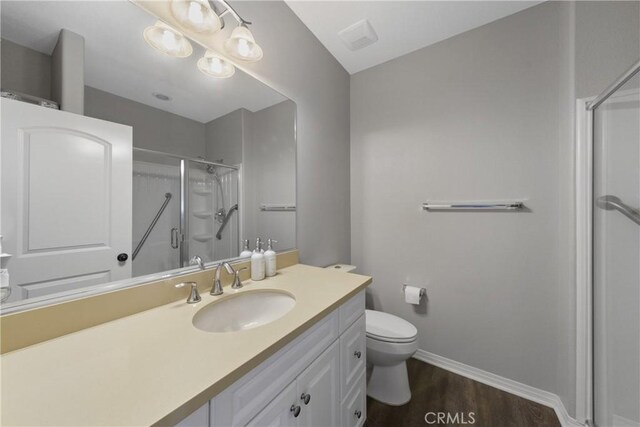 bathroom with a shower with door, vanity, wood-type flooring, and toilet