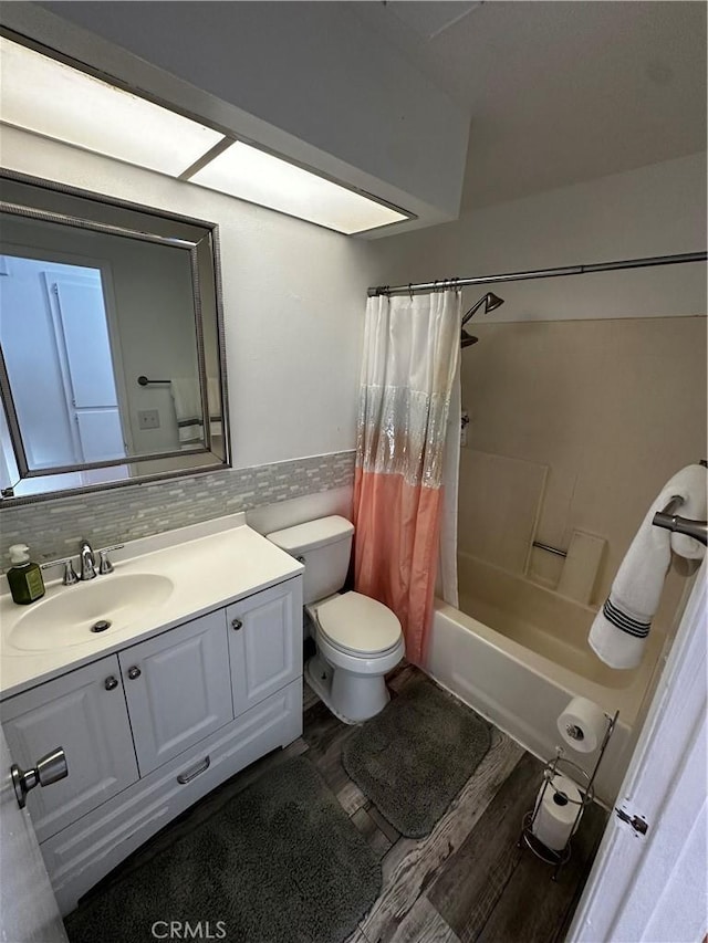 full bathroom with wood-type flooring, toilet, decorative backsplash, shower / bath combo with shower curtain, and vanity