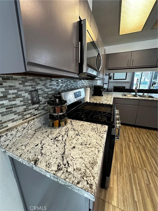 kitchen featuring light stone countertops, sink, stainless steel appliances, light hardwood / wood-style flooring, and kitchen peninsula