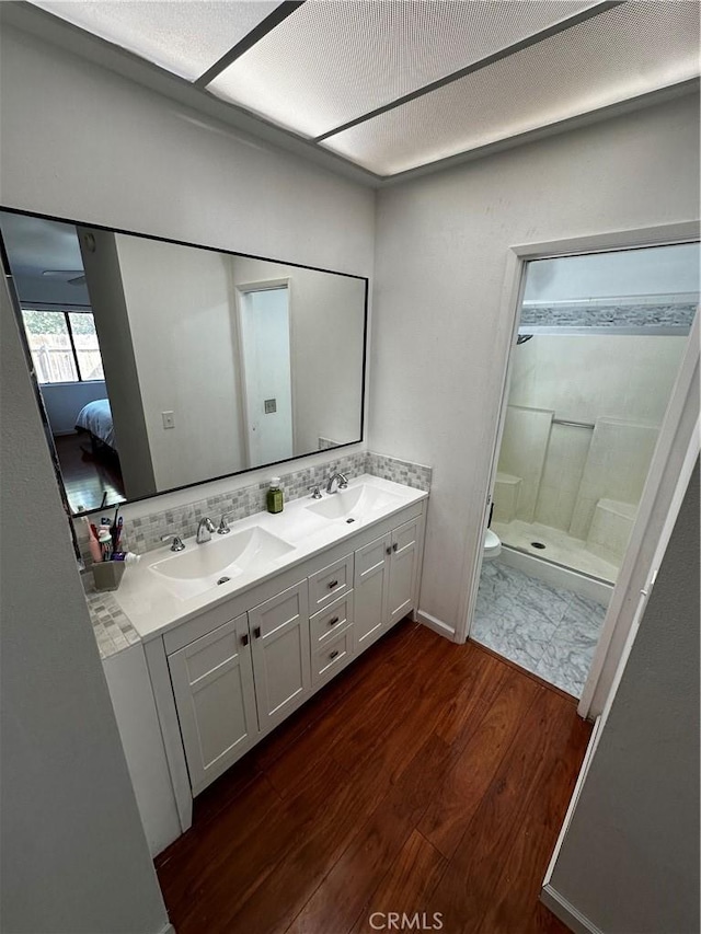 bathroom featuring hardwood / wood-style flooring, vanity, toilet, and a shower