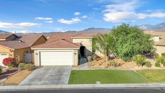 view of front facade with a mountain view, a front yard, and a garage