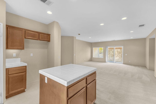 kitchen featuring tile countertops, a center island, and light colored carpet