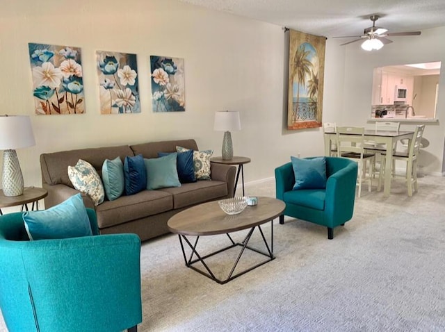 living room with ceiling fan, carpet floors, and a textured ceiling