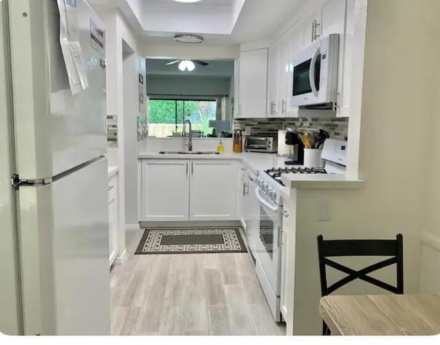 kitchen featuring white cabinets, light wood-type flooring, white appliances, and sink