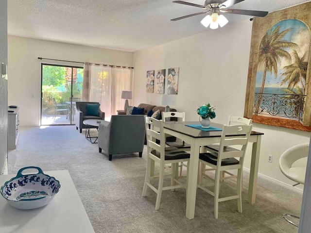 carpeted dining space with ceiling fan and a textured ceiling